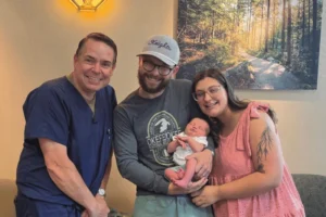 PREG fertility specialist with parents and their newborn after fertility treatment